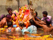 Indian devotees immersing the Hindu god Ganesha during Ganesh Chaturthi, a popular 11-day religious festival annually celebrated across India.