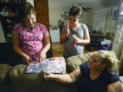 Sisters Kaylynn, left, and Emily Ward look at newspaper advertisements with their mom, Ginger Marcom, at Marcom&#039;s sister&#039;s apartment in Vancouver in November. The family has been staying with friends and family after Marcom&#039;s former landlord sold the property they were renting and gave them less than 30 days to move. Marcom recently found a home that will accept her Section 8 housing voucher, but is struggling to afford the deposit.