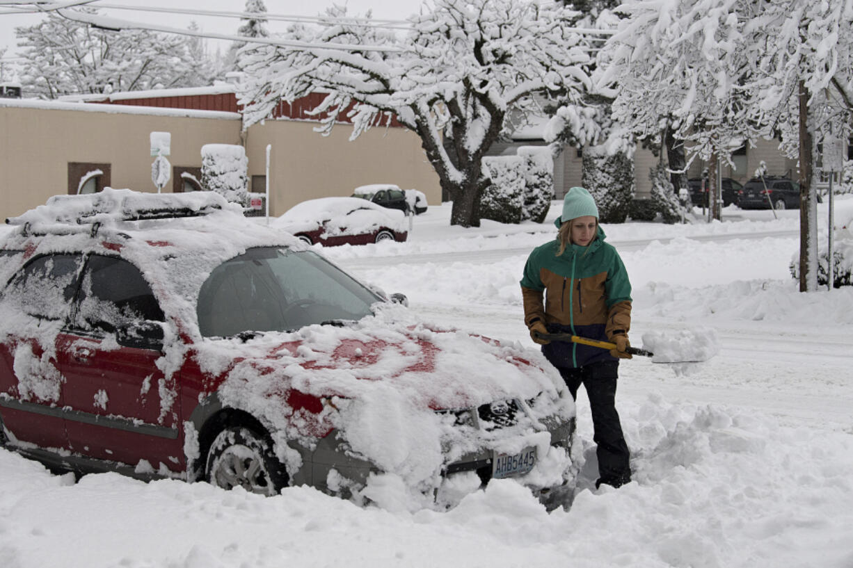 Kim Kathrein of Vancouver clears snow from around her car in downtown Vancouver on Wednesday morning, Jan. 11.