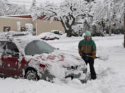 Kim Kathrein of Vancouver clears snow from around her car in downtown Vancouver on Wednesday morning, Jan. 11.