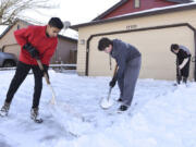 Dhruv Desai, 13, from left, Randall Conner, 10, and Greg Conner, 13, shovel the snow off a neighbor&#039;s driveway near Southeast 19th Street and Southeast 173rd Avenue in Vancouver on Thursday.