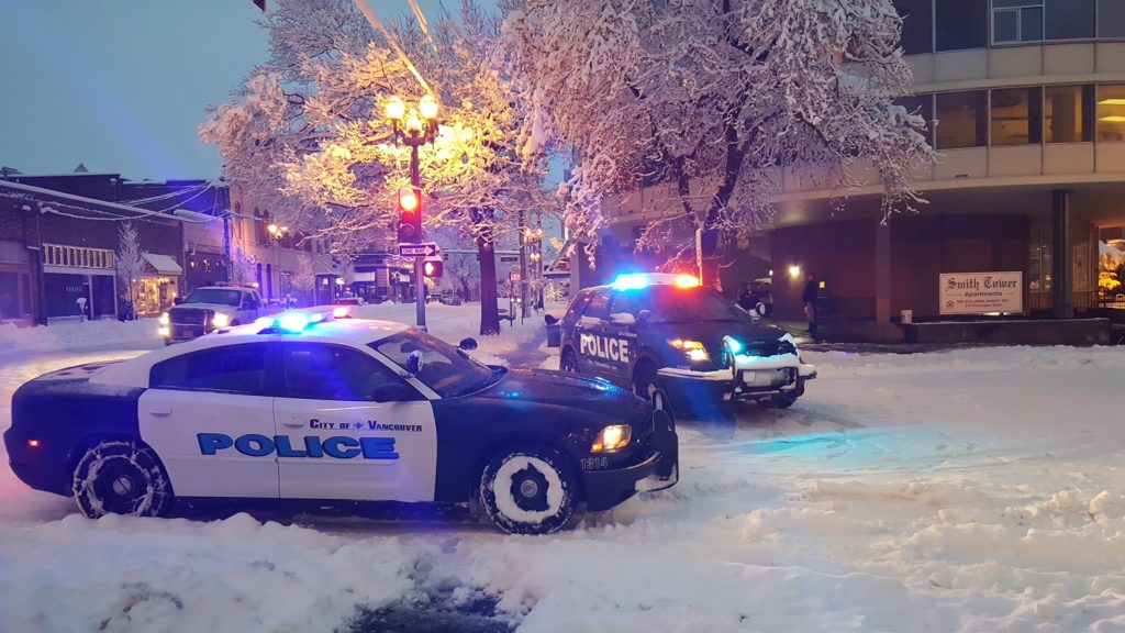 Vancouver police vehicles block the intersection at Sixth and Washington in downtown for a power line brought down by a snow-covered branch.