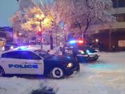 Vancouver police vehicles block the intersection at Sixth and Washington in downtown for a power line brought down by a snow-covered branch.