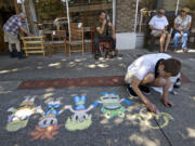 Jay Morton, 26, of Vancouver, draws characters on the sidewalk on Main Street in Vancouver during the fourth annual "Chalk the Walks" in Uptown Village in  2014.