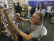 Charles Tovar of Forest Grove, Ore., restores a painting as Mary Barbaro of Portland watches Sunday at the 12th annual Clark County Antique &amp; Collectible Show.