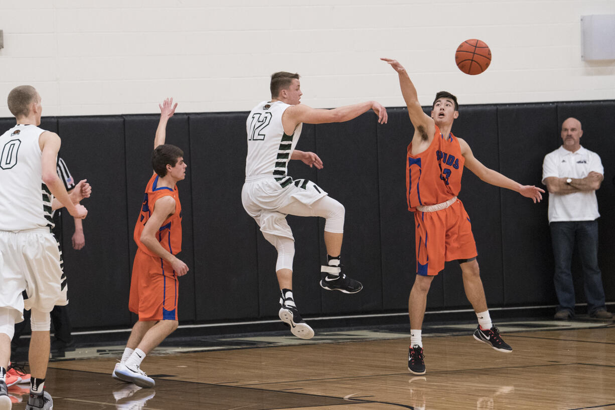 Ridgefield’s Kellen Bringhurst (33) and Woodland’s Tyler Flanagan (12) reach for the ball during the second quarter at Woodland High School, Tuesday January 31, 2017.