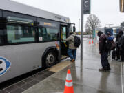 Dressed for the weather, passengers board a bus on The Vine at the Vancouver Mall Transit Center. Weather conditions moved C-Tran to use its typical 40-foot buses rather than its Vine-specific 60-footers on the Vine&#039;s opening day.