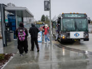 Passengers cope with cold, wet weather to catch The Vine from the Vancouver Mall Transit Center on Sunday. The service operated with regular buses and on a modified route on its opening day due to adverse weather conditions.