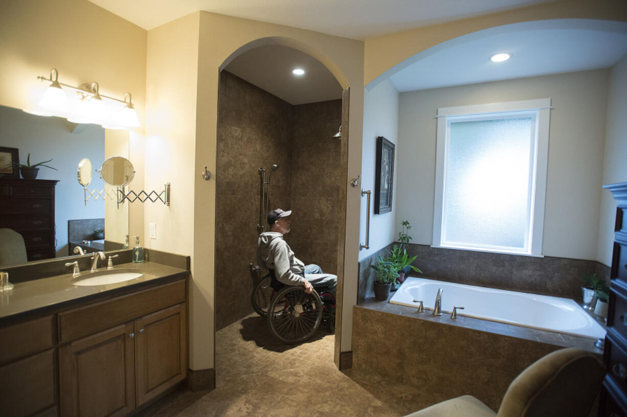 Chuck Frayer of the Clark County Commission on Aging looks over the walk-in shower in Marian Anderson&#039;s Hazel Dell home Tuesday morning. It has an adjustable shower head and a seat.