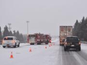 Traffic squeezes by the scene of a crash on northbound Interstate 5 near Northeast 78th Street in Hazel Dell on Saturday. Roads slickened by afternoon snowfall led to numerous crashes, spinouts and rollovers on Clark County roads.