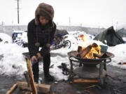 Tiffany Singleton chops firewood outside her tent on West 12th Street in Vancouver on Wednesday. After nearly a foot of snow hit Vancouver Tuesday evening, those living on the streets near the Share House were welcomed Wednesday afternoon by volunteers passing out warm beverages, coats and gloves.