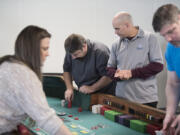 Yacolt resident Charley Cellers, second from left, learns more about the game of craps from instructor Bill Caswell, with maroon sleeves, during a class at the Ilani Casino Resort on Friday morning.