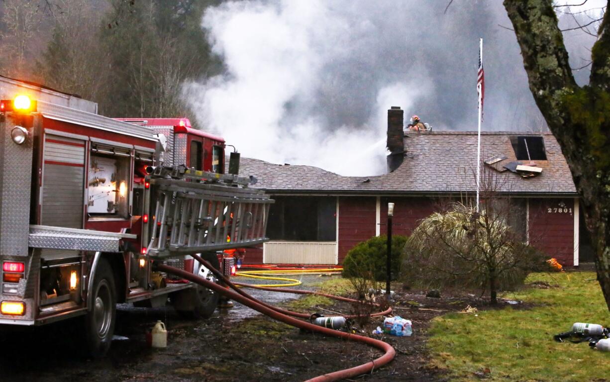 ​​A firefighter works to extinguish the remnants of an attic fire that did significant damage Saturday to a house at 27801 N.E.