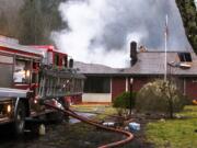 ​​A firefighter works to extinguish the remnants of an attic fire that did significant damage Saturday to a house at 27801 N.E.