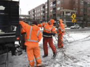 Mike McDonald, with the Vancouver Department of Public Works grounds division, center, tosses fallen tree branches into a utility truck at Esther Short Park on Wednesday.