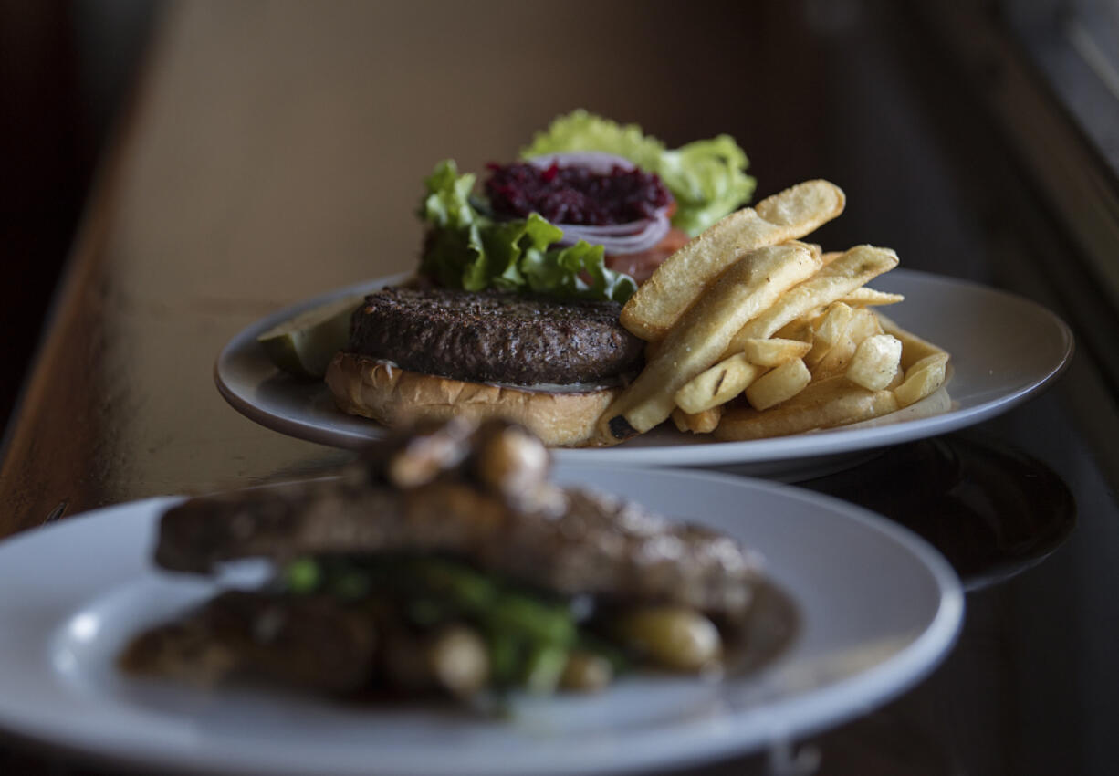 The New York strip steak, foreground, is served Jan. 27 along with the elk burger, in focus, at Uptown Barrel Room in Vancouver.