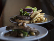 The New York strip steak, foreground, is served Jan. 27 along with the elk burger, in focus, at Uptown Barrel Room in Vancouver.