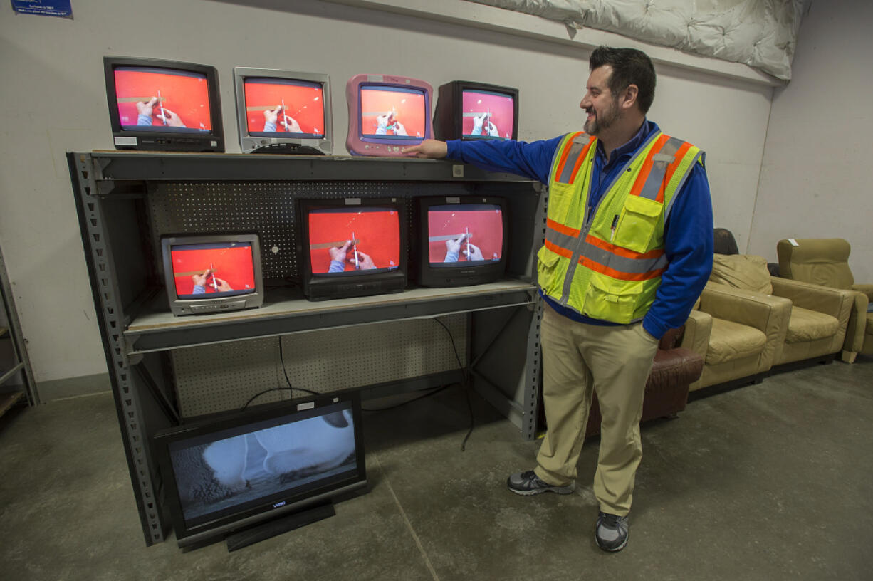 Goodwill Vancouver Outlet manager Jason Pickering looks over a selection of televisions for sale at Goodwill Vancouver Outlet on the morning of Jan. 18. Goodwill received nearly 1.5 million pounds of donated TVs last year from county residents.