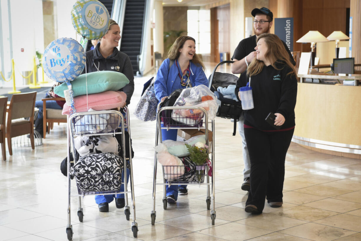 Ashley Burkett, right, laughs with nurses Mandy Westervelt, center, and Rachel Wulf, left, while Ashley&#039;s husband, Aaron Burkett, carries their 3-day-old son, Jackson Burkett, through Legacy Salmon Creek Medical Center on Wednesday. The Burketts were driven home from Legacy Salmon Creek by a volunteer from the Clark County Sheriff&#039;s Search and Rescue because the nearly foot of snow that fell Tuesday evening created difficult road conditions in Vancouver Wednesday.