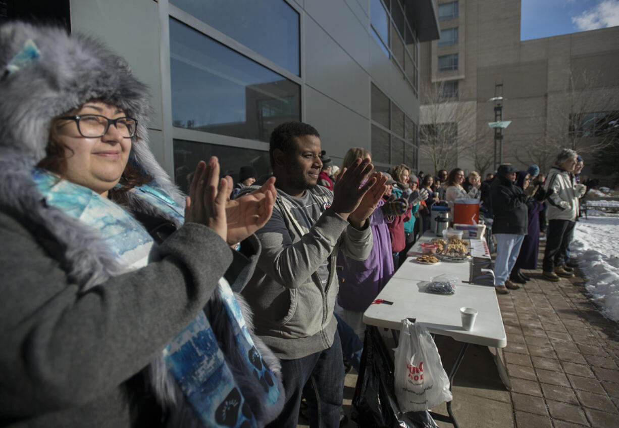 Giovanna Larrea of Vancouver, left, joins James Tolson, president of Concerned Humans Against Poverty, second from left, as they applaud speakers during a Vancouver rally Monday on Dr. Martin Luther King Jr. Day.