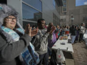 Giovanna Larrea of Vancouver, left, joins James Tolson, president of Concerned Humans Against Poverty, second from left, as they applaud speakers during a Vancouver rally Monday on Dr. Martin Luther King Jr. Day.