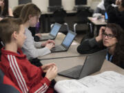 Seventh-grader Colton Sahota, 12, left, talks with teacher Beth Doughty, right, as she answers questions from students while they work on their Dell Chromebooks at Chief Umtuch Middle School in Battle Ground on Thursday morning. The district is putting a levy before voters on Feb. 14. Part of the funding supports technology in classrooms.