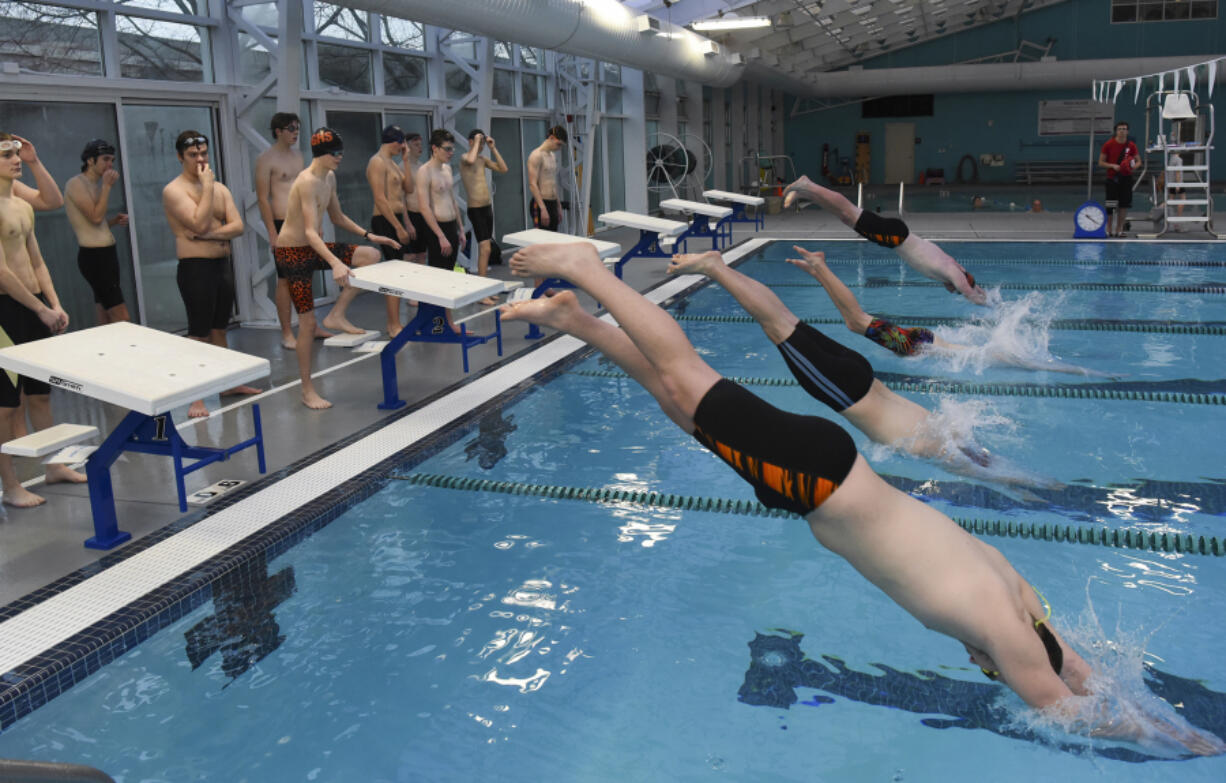 Battle Ground and Prairie High School boys swim team members dive into the pool during practice at the Clark County YMCA, Thursday.