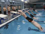 Battle Ground and Prairie High School boys swim team members dive into the pool during practice at the Clark County YMCA, Thursday.