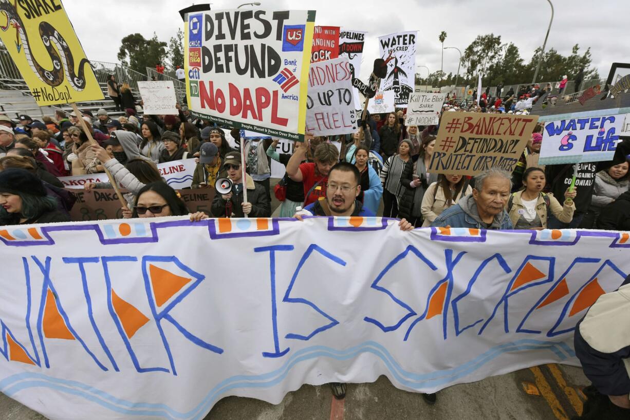 File - In this Jan. 2, 2017, file photo, protesters rally against the Dakota Access Pipeline behind the 128th Rose Parade in Pasadena, Calif. The front lines of the battle against the $3.8 billion Dakota Access pipeline are shifting away from the dwindling encampment in North Dakota.