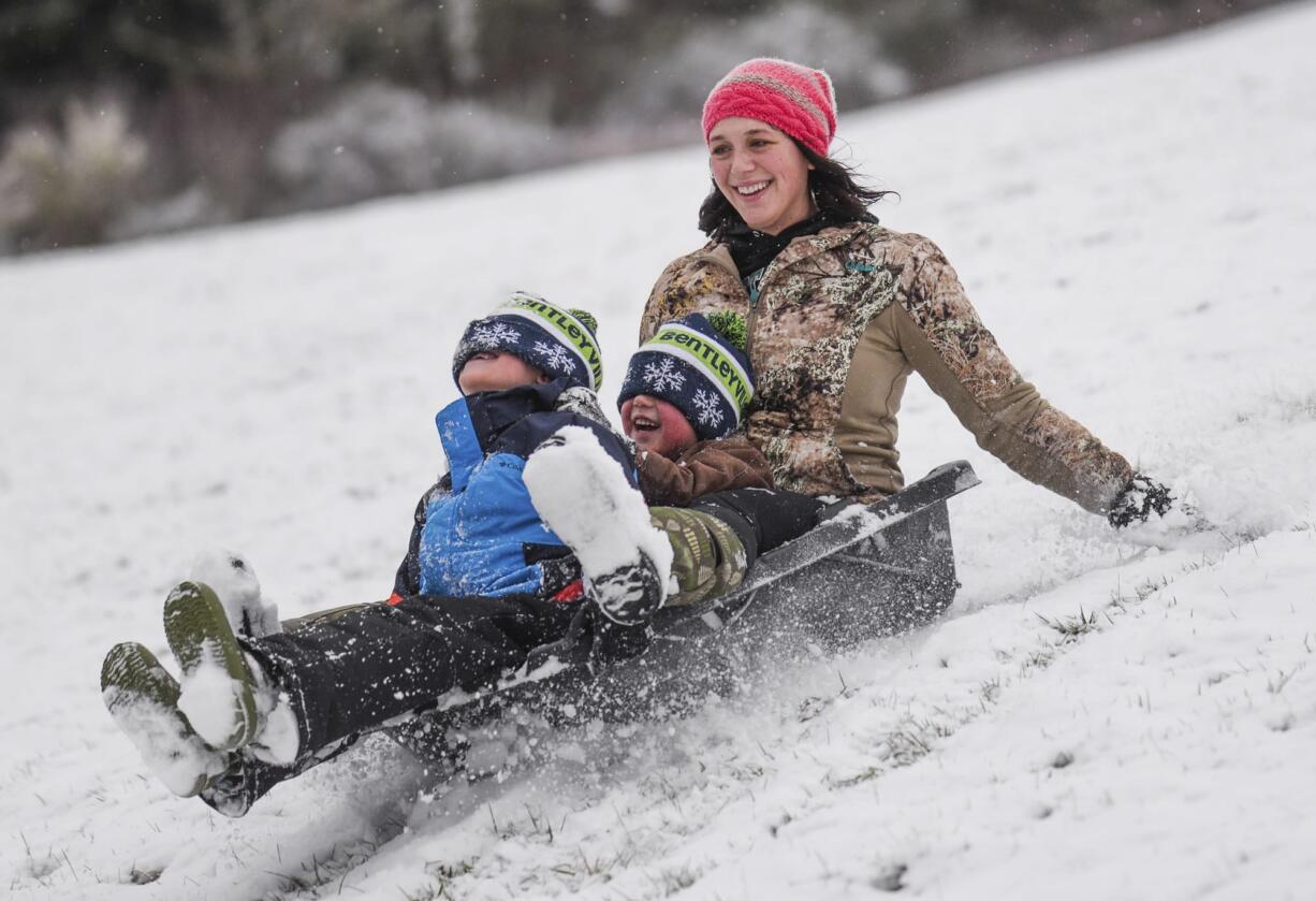 Alex Hanson sleds down the Astoria Column hill with her two sons Byron Hanson, center, and Henry Hanson on Wednesday, Jan. 11, 2017, in Astoria, Ore.