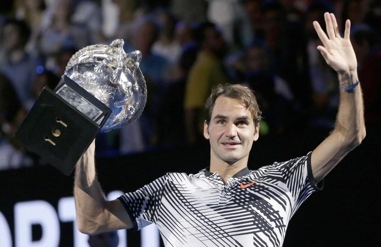 Switzerland's Roger Federer waves while he does a lap of honor with his trophy after defeating Spain's Rafael Nadal in the men's singles final at the Australian Open tennis championships in Melbourne, Australia, Sunday, Jan. 29, 2017.