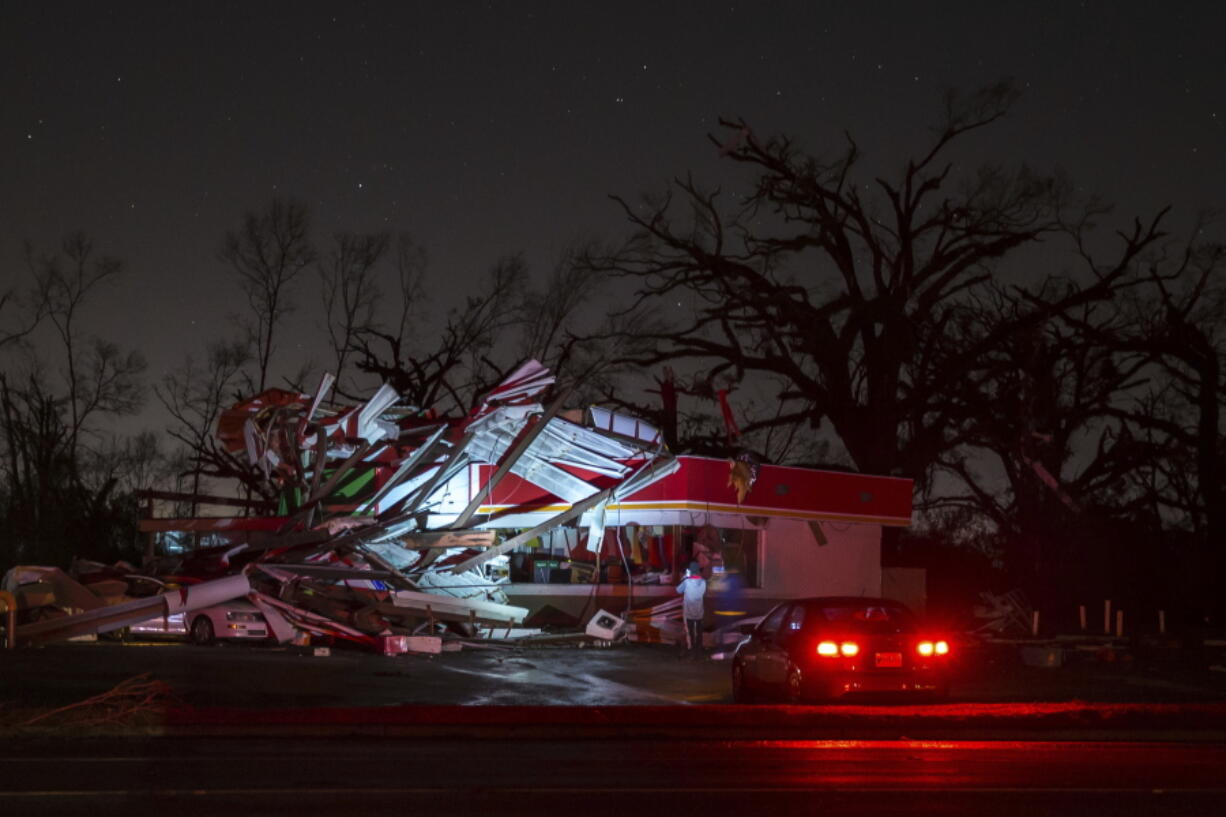 A vehicle stops Sunday to photograph a gas station damaged by an apparent tornado in Albany, Ga.