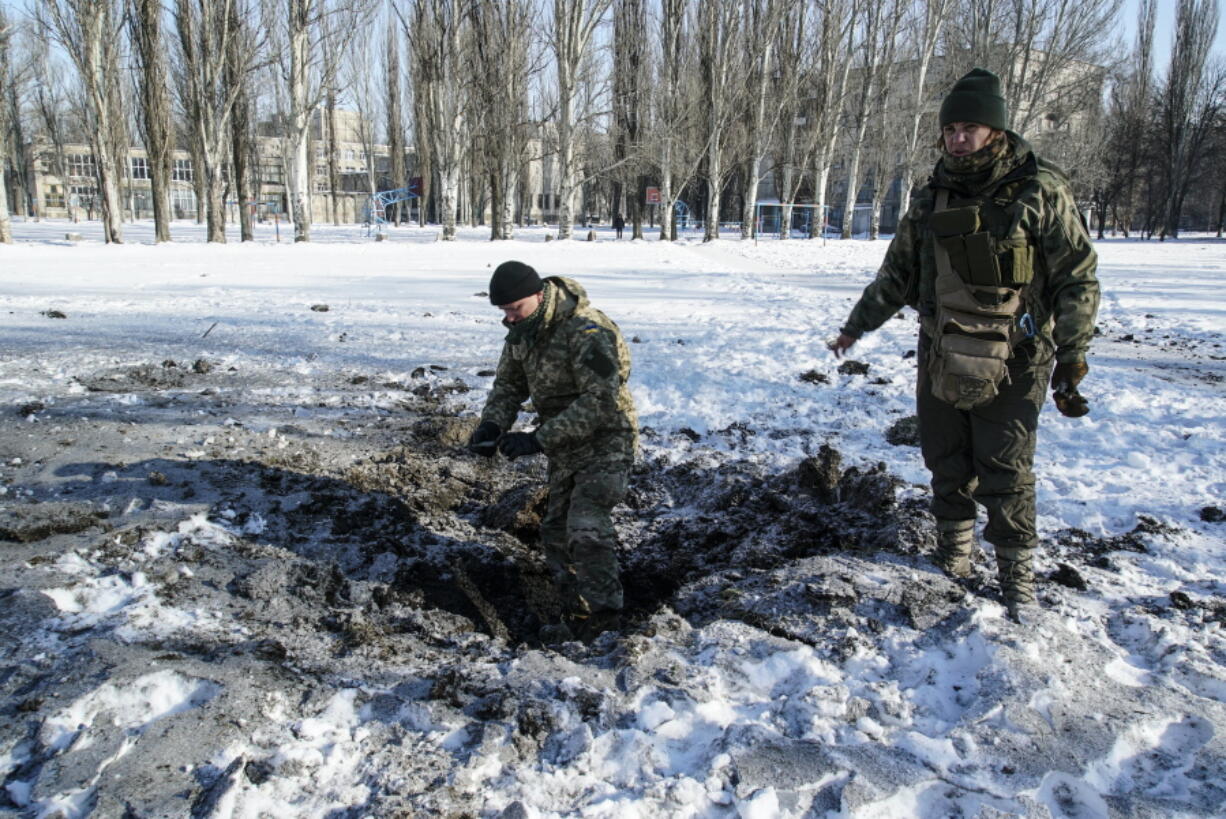 A Ukrainian soldier inspects a crater left by an explosion Tuesday in Avdiivka, Ukraine. More than 10 people were killed in fighting late Monday and early Tuesday.