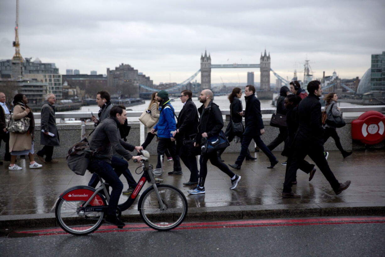 During the morning rush hour Monday, people walk across London Bridge backdropped by Tower Bridge in London. Millions of commuters are facing delays and frustration as a strike by London Underground station staff shuts down much of the subway network.