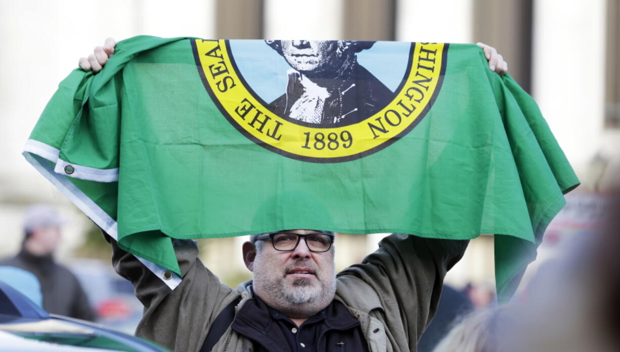 Alfred Frates, a health care worker and union member who said he supports education funding, holds a Washington state flag Monday during a rally in support of education funding at the Capitol in Olympia, Wash. Lawmakers in the current legislative session are working to comply with a 2012 Washington Supreme Court ruling that mandates fully funding the state&#039;s basic education system. (AP Photo/Ted S.