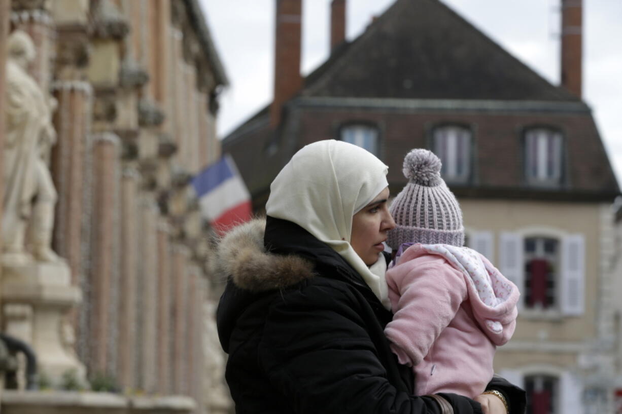 Iman Mshanati holds her 6-month-old daughter Layan outside the town hall of Gray, eastern France.  The Syrian family of Alahamad was among the lucky few accepted so far into a European relocation program.