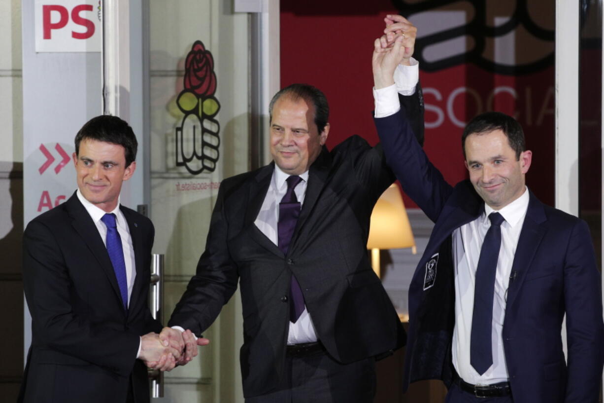 Former Socialist Prime Minister Manuel Valls, left, and Benoit Hamon, wave to supporters at the socialist party headquarters in Paris, Sunday, Jan. 29, 2017. Hamon, riding to victory from left-wing obscurity on a radical proposal to a pay all adults a monthly basic income, will be the Socialist Party candidate in France&#039;s presidential election after handily beating Valls in a primary runoff vote. At center is Jean-Christophe Cambadelis, head of the Socialist party.