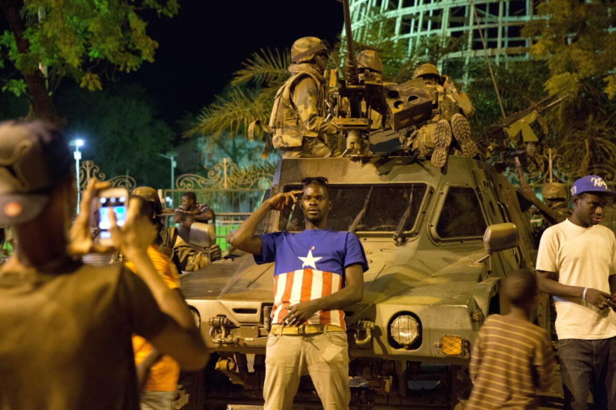 People pose as Senegalese troops with the Ecowas alliance secure the area near to the state house in the Gambian capital Banjul Sunday Jan. 22, 2017, one day after Gambia&#039;s defeated leader Yahya Jammeh went into exile.