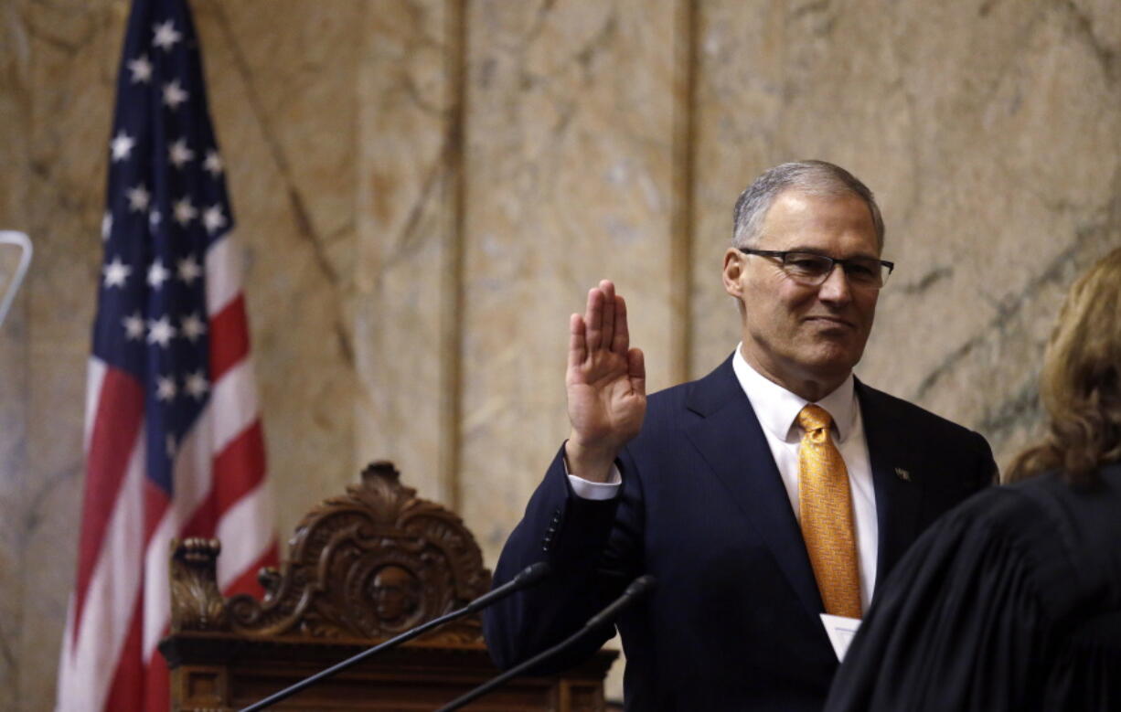 Gov. Jay Inslee takes the oath of office Wednesday before his inaugural address to a joint session of the Legislature as he begins his second term in Olympia.