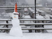 A snowman wearing a traffic cone hat is shown on an overpass as early morning traffic is at a standstill in the background on Interstate 5 headed into Portland, Wednesday, Jan. 11. A snowstorm spread through Portland and parts of Washington state overnight, toppling trees, closing schools and cutting power to thousands.