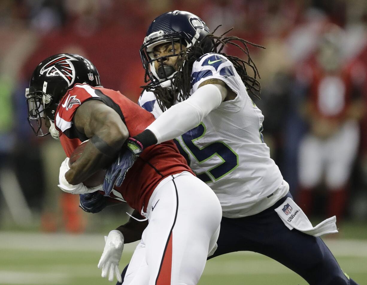 Seattle Seahawks cornerback Richard Sherman (25) tackles Atlanta Falcons wide receiver Julio Jones (11) during the first half of an NFL football NFC divisional playoff game, Saturday, Jan. 14, 2017, in Atlanta.