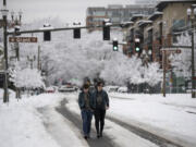 Cassiopeia Rivera, left, and McKenzie Prior walk through the streets in downtown Vancouver Wednesday afternoon. Many sidewalks in the city are still choked with snow.