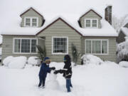 Vancouver resident Kate Mattos, 8, left, and her brother, Kenny, 10, build a snowman in the front yard of their home in Northwest Vancouver on Wednesday morning. Vancouver Public Schools and other districts closed school Wednesday and Thursday in light of the heavy snow.