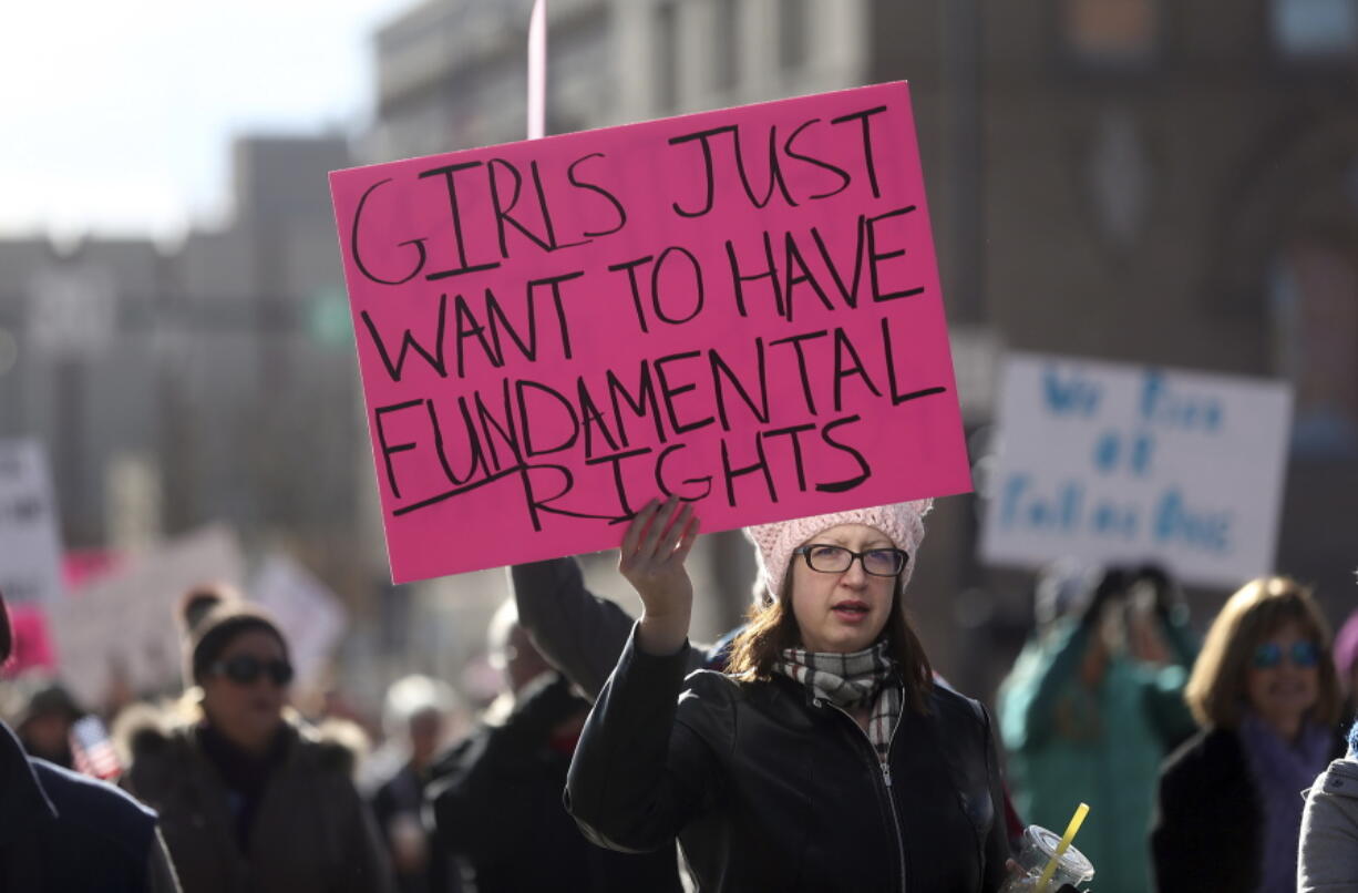 A woman walks with others in support of women and minorities during a Women&#039;s March along Capitol Avenue Saturday, JAN. 21, 2017,  in downtown Cheyenne, Wy. Around 1,500 and 2,000 people took park in the march to focus on the rights of women and other minority and disadvantaged groups.