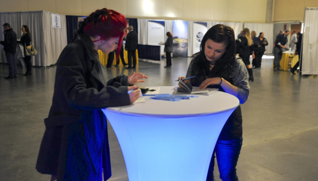 Greg Wahl-Stephens for the Columbian 
 Adrienne Martin, left, and Ashley Wallace examine handouts at a January job fair held by the Ilani Casino Resort. About 70 percent of 1,000 employees have been hired so far. (Amanda Cowan/The Columbian)