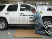 Kai Crown applies decals to sheriffs&#039; office vehicles at International Graphics and Nameplate in Vancouver.