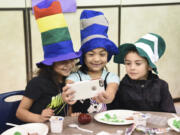 First-graders Niveya Rincon-Johnson, from left, Camille Winslow and Silas Ledesma take a selfie with a parent volunteer&#039;s phone while eating green eggs and ham provided by Beaches Restaurant &amp; Bar on Monday. Students are celebrating Read Across America week in recognition of Dr. Seuss&#039; upcoming birthday.