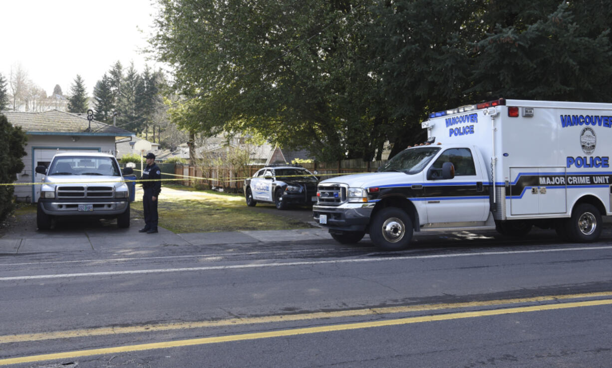 A Vancouver Police Department officer walks Friday around a house on East 18th Street in Vancouver where officers arrested one man and reported there was a body inside.