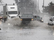 Drivers navigate standing water Sunday afternoon on state Highway 503 near Northeast 87th Street in the Orchards area.