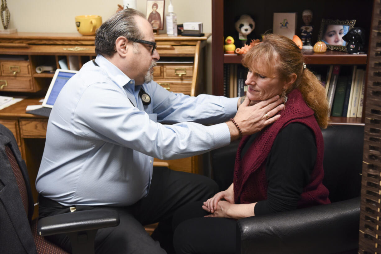 Dr. Dino Ramzi checks patient Wendi Deans&#039; sore neck during an appointment Feb. 10 at his clinic, Patient Direct Care, in Battle Ground. The clinic uses a model called direct primary care, in which people pay a monthly fee for access to primary care services.